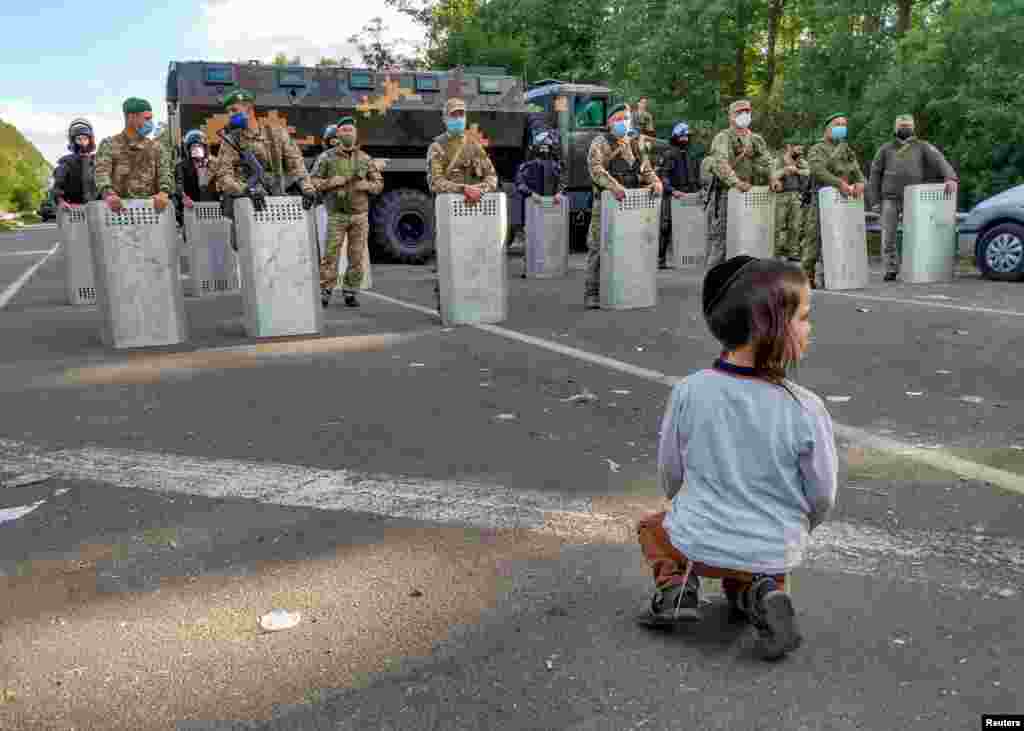 A Jewish pilgrim, who plans to enter Ukraine for a pilgrimage from Belarus, sits in front of Ukrainian service members near Novi Yarylovychi crossing point in Chernihiv Region, Ukraine Sept. 15, 2020. (Credit: BelaPAN)