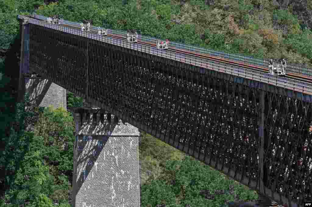 People cross the Viaduc des Fades as they ride the 'vélorail' on an old railway line in Les Ancizes-Comps, central France, Aug. 18, 2020.