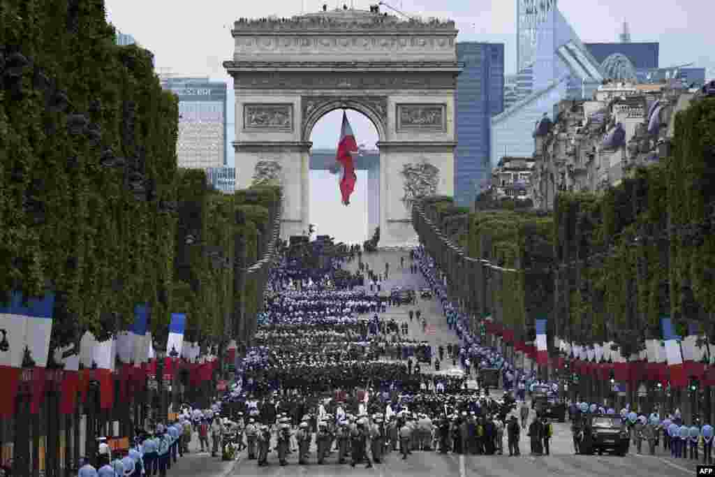 Pasukan militer menunggu di tugu Arc de Triomphe di Paris, Perancis sebelum perayaan parade militer tahunan Hari Bastille di jalan Champs-Elysees.