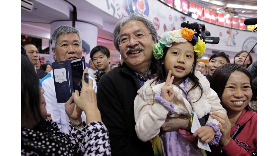 Chief Executive candidate, Hong Kong's former Financial Secretary John Tsang Chun-wah, center, holds a child as he poses for a photograph with his supporters at a election campaign in Hong Kong, March 16, 2017.