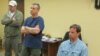 In this handout photo provided by the Russian security service, a man claimed by FSB to be Ryan Fogle, right, a third secretary at the U.S. Embassy in Moscow, with embassy officials at left, sits in the the FSB offices in Moscow, May 14, 2013. 