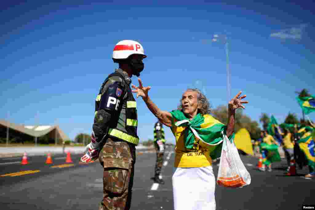 A supporter of Brazil's President Jair Bolsonaro talks with a soldier during a protest against the country's Supreme Federal Court, in front of the army headquarters in Brasilia.