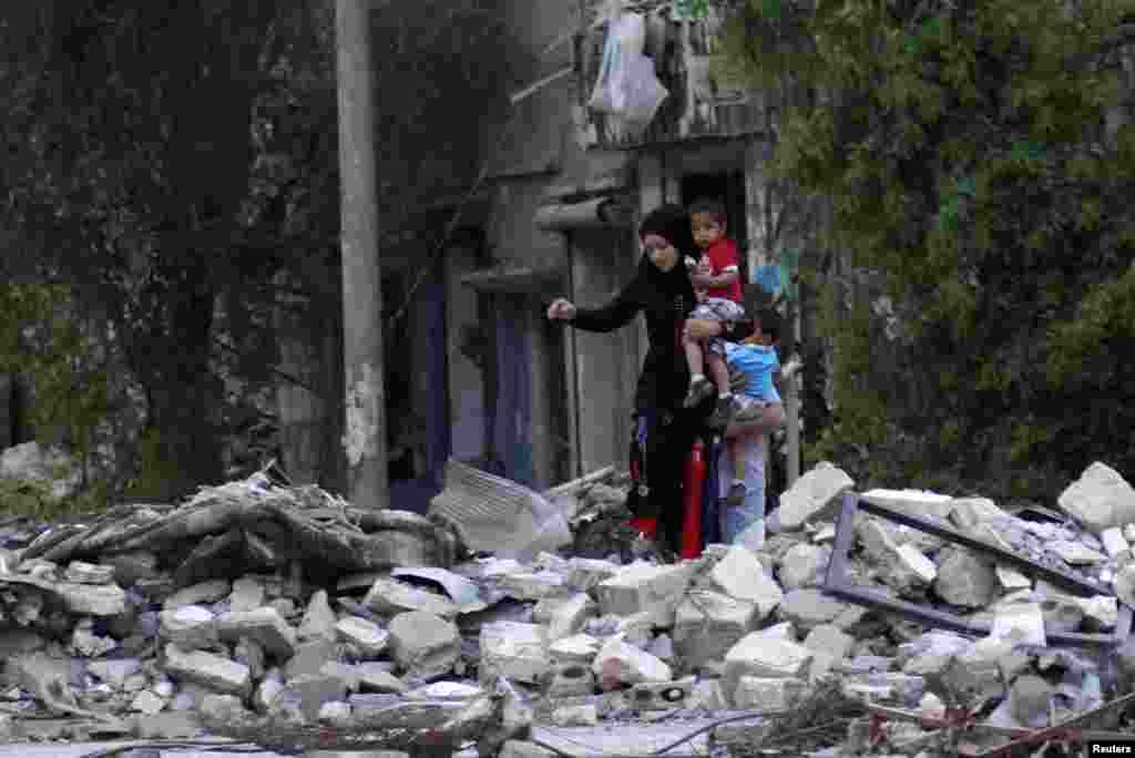 A woman carries her child as she walks on rubble in a neighbourhood in Deir al-Zor, Syria, April 15, 2013.