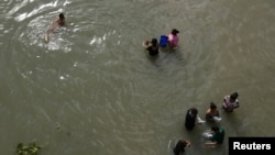 Migrantes lavan ropa en el río Grande cerca de un improvisado campamento ocupado por solicitantes de asilo en el puente internacional Gateway en Matamoros, Tamalipas, México, el 28 de octubre de 2019.