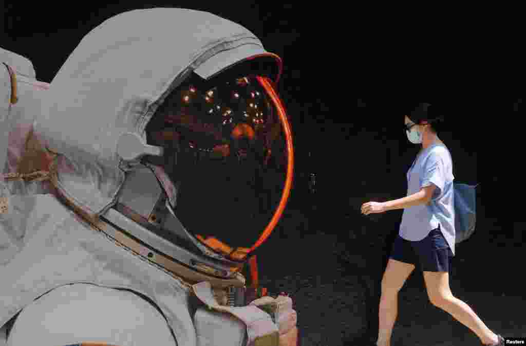 A woman wearing a face mask walks past a mural, during the coronavirus disease outbreak, in Hong Kong, China.