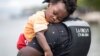 Un migrante haitiano sostiene a su hijo antes de abordar un bote hacia Capurganá, cerca de la frontera con Panamá, el miércoles 28 de julio de 2021, en Necoclí, Colombia. [AP Foto/Iván Valencia]