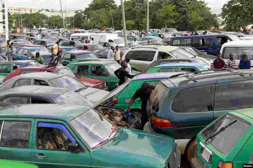 Um homem coloca água no radiador do carro enquanto espera nas filas incríveis para abastecer o carro. Abuja, Nigéria 25 de Maio 2015
