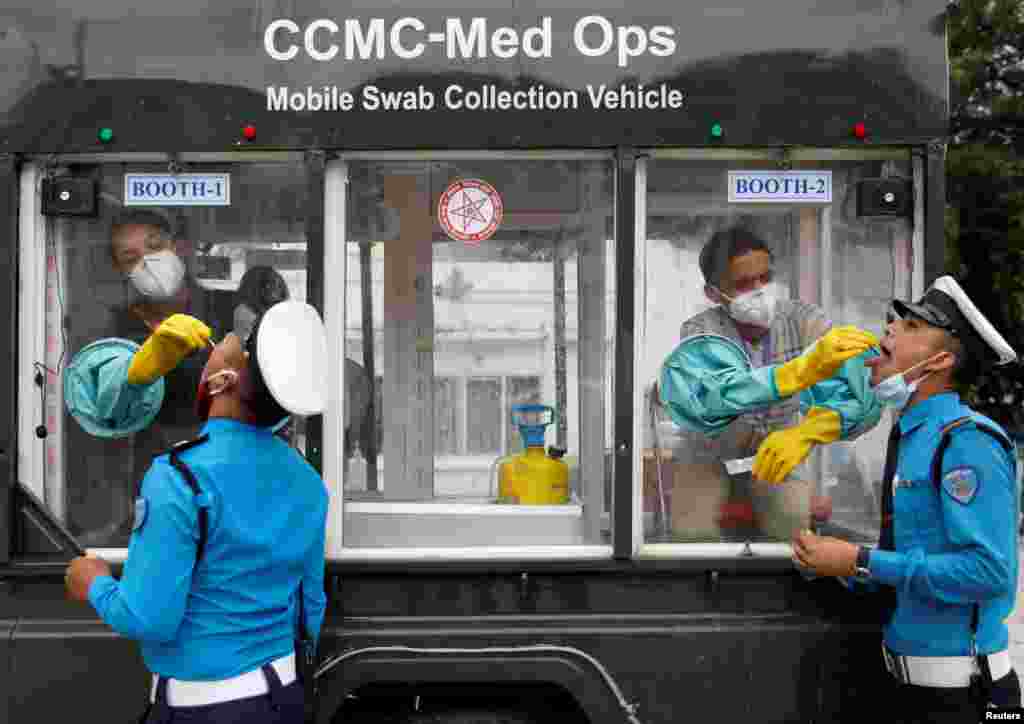 Health officials take a swab sample for the coronavirus disease (COVID-19) from traffic policemen at Singha Durbar office complex, that houses the Prime Minister's office and other ministries, in Kathmandu, Nepal.