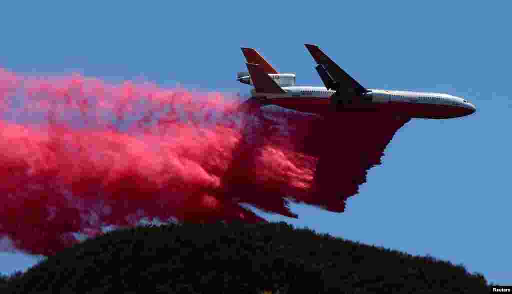A DC-10 fire fighting aircraft makes a retardant drop as fire fighters continue to battle the so-called Sand Fire in the Angeles National Forest near Los Angeles, California, July 25, 2016.