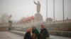 Ethnic Uighurs sit near a statue of China's late Chairman Mao Zedong in Kashgar, Xinjiang Uighur Autonomous Region, China, March 23, 2017. 