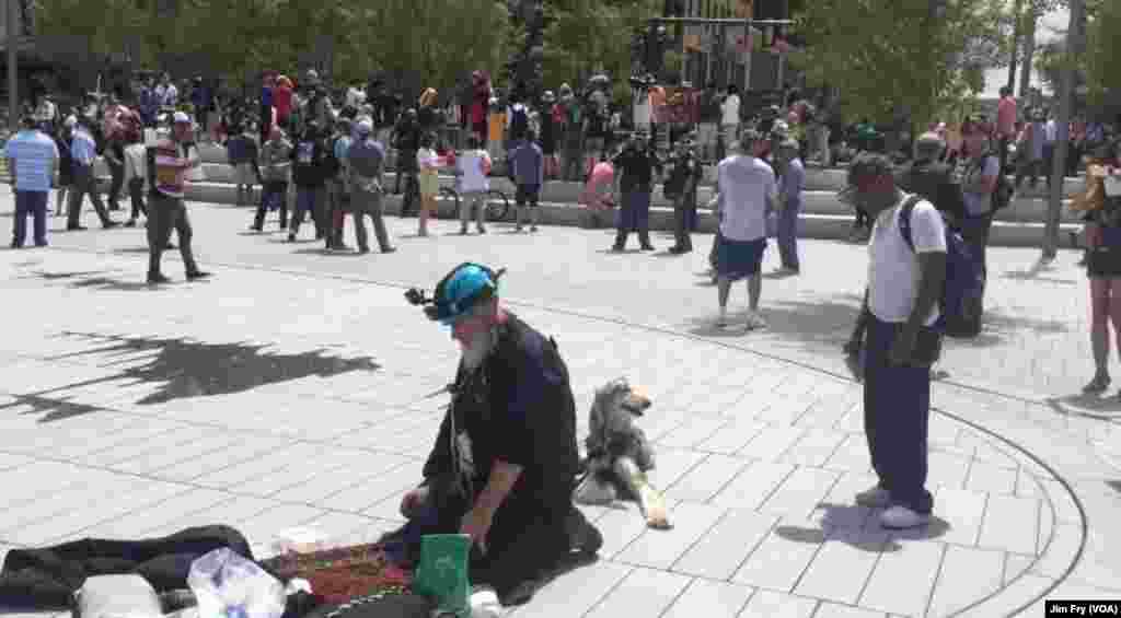William Hale watches as Mohamed Omar of Washington, D.C., prays in the downtown Public Square, in Cleveland, July 18, 2016. Omar said he traveled to Cleveland by himself.