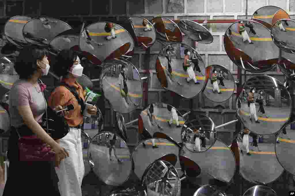 People wearing face masks are reflected in mirrors at a subway station in Seoul, South Korea.