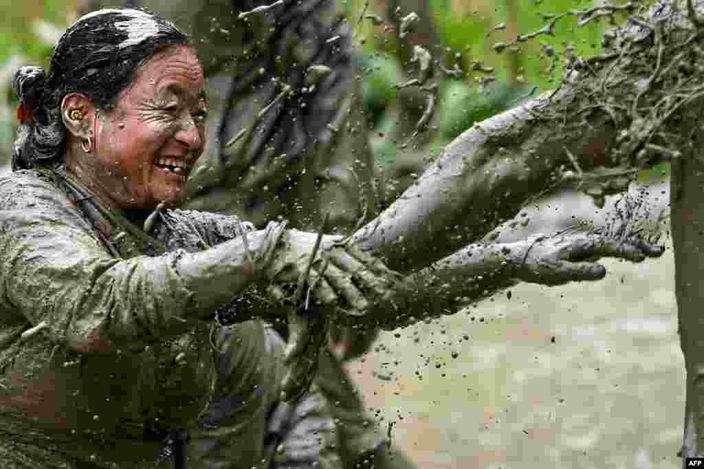 Mud-covered farmers play in a rice paddy field during "National Paddy Day", which marks the start of the annual rice planting season, in Tokha village on the outskirts of Kathmandu, Nepal.