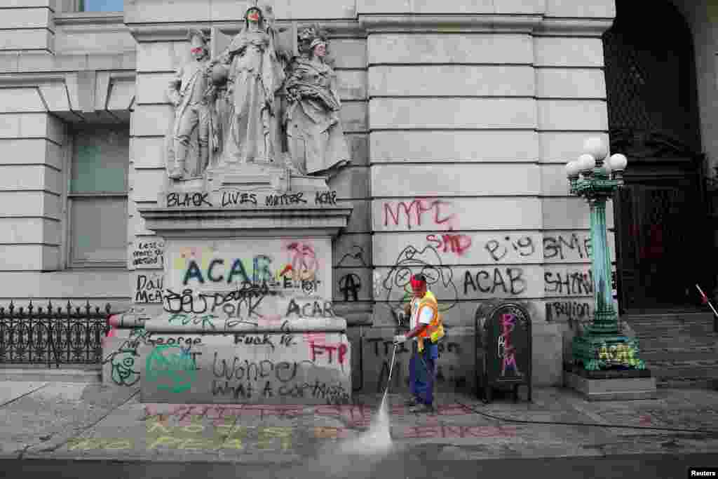 A worker washes the sidewalk to remove graffitis after police dismantled the "City Hall Autonomous Zone" that was in support of the Black Lives Matter movement in the Manhattan borough of New York City.