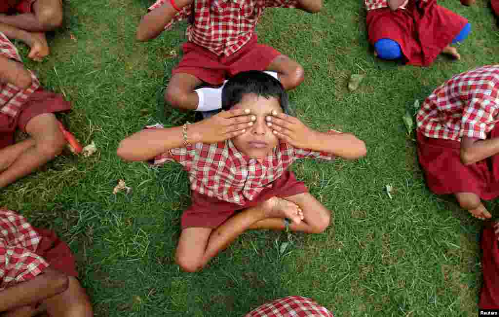 Para murid sekolah berlatih yoga menjelang perayaan Hari Yoga se-Dunia di Agartala, India.