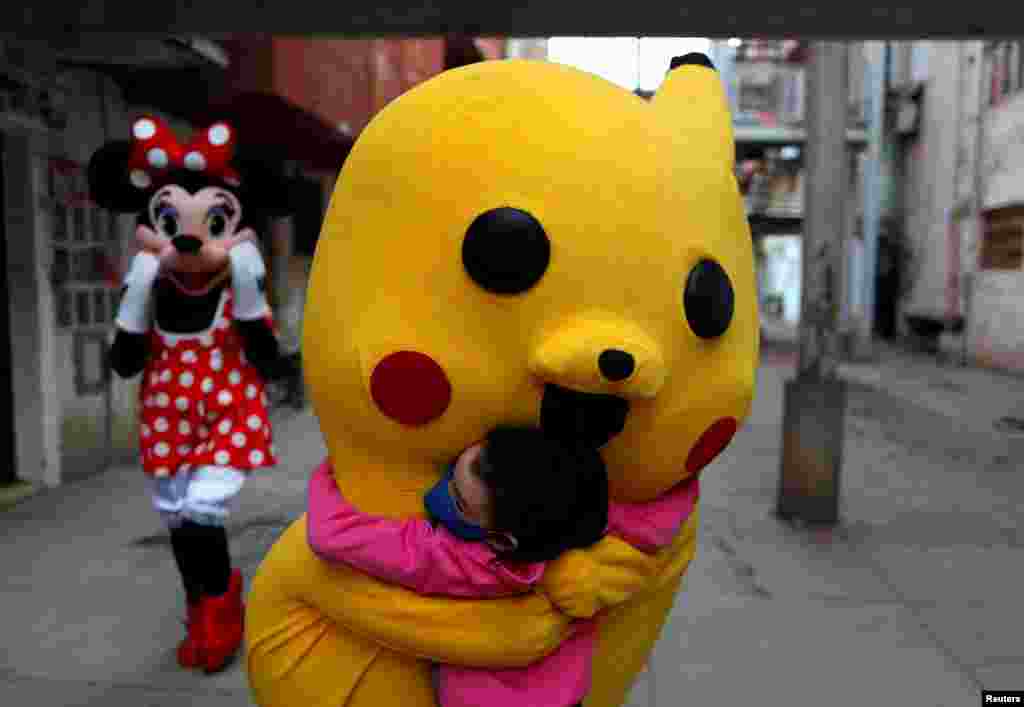 A volunteer wearing a costume of Pokemon character Pikachu hugs a child during Children's Day, in Fuerte Apache, in Buenos Aires, Argentina, Aug. 16, 2020.