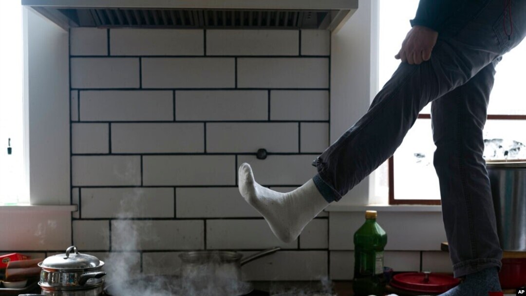 Jorge Sanhueza-Lyon stands on his kitchen counter to warm his feet over his gas stove in Austin, Texas, Feb. 16, 2021.
