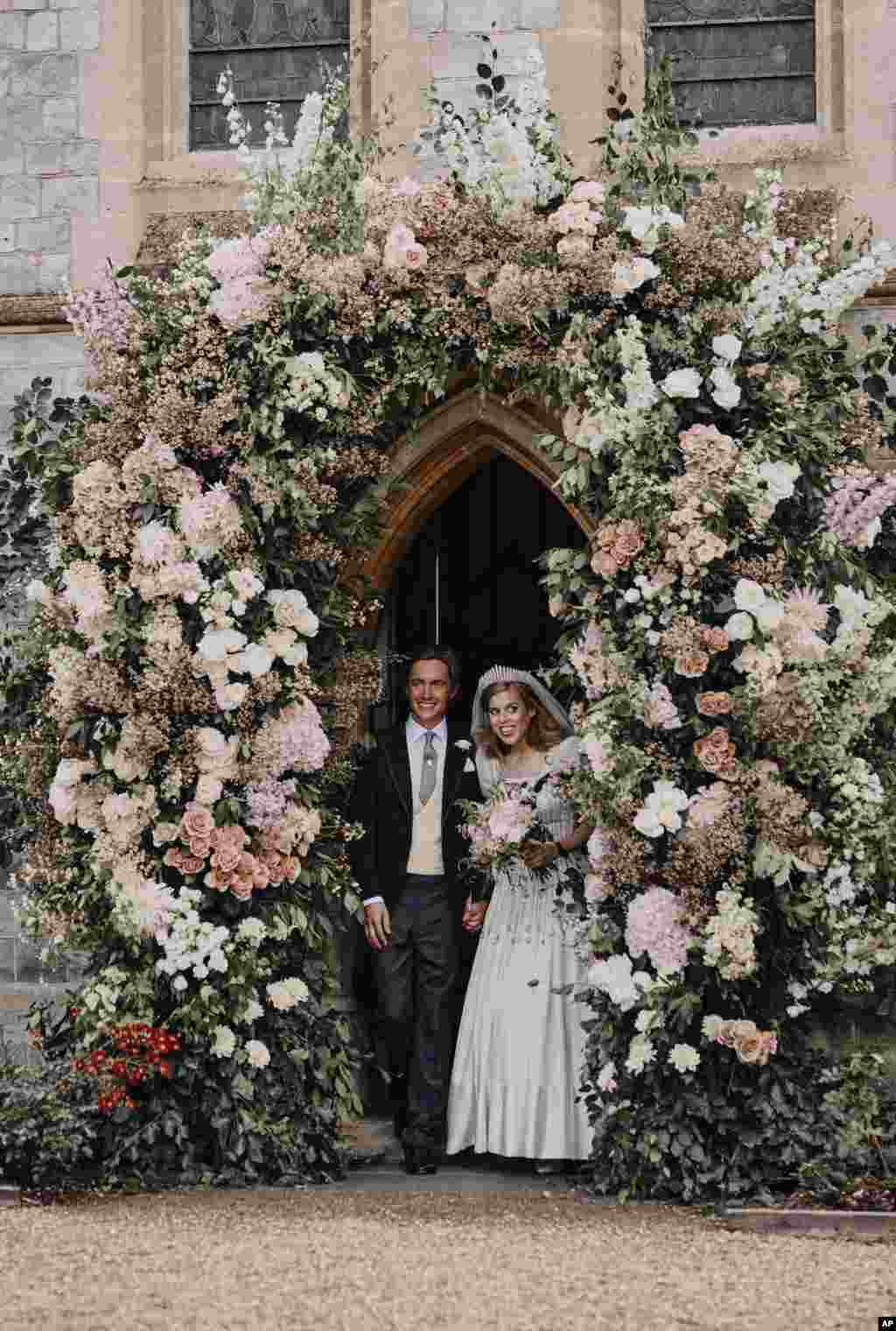 In this photograph released by the Royal Communications of Princess Beatrice and Edoardo Mapelli Mozzi, Britain's Princess Beatrice and Edoardo Mapelli Mozzi stand in the doorway of The Royal Chapel of All Saints at Royal Lodge, Windsor, England, after their wedding, July 18, 2020. Princess Beatrice wore a vintage dress loaned to her by Queen Elizabeth II at her wedding, Buckingham Palace said.