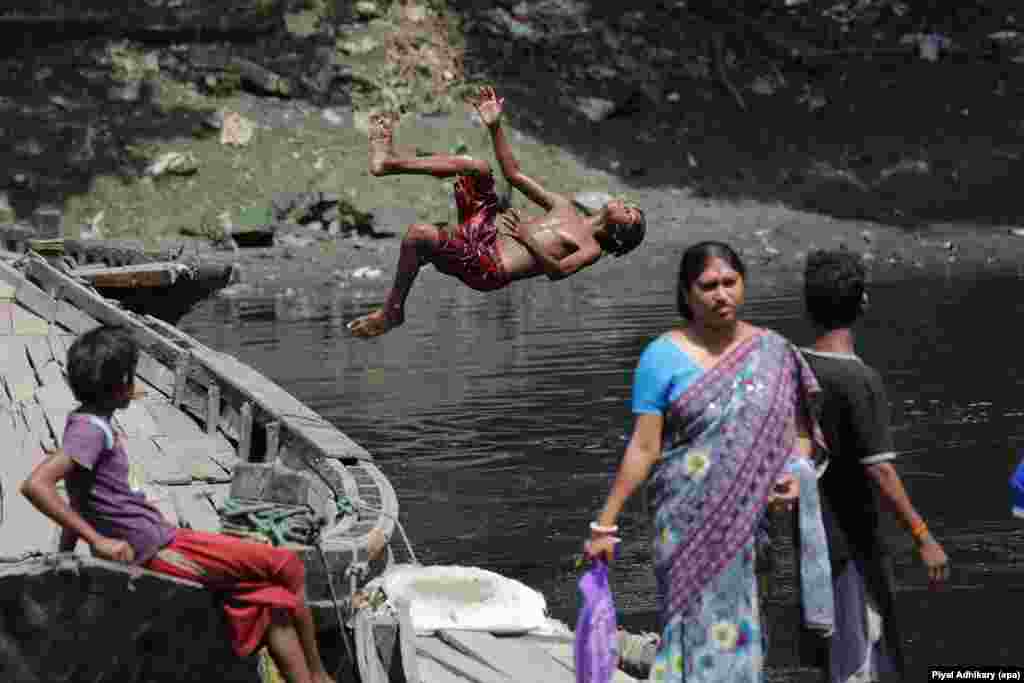 Seorang anak India melompat di sungai Adi Ganga untuk mengumpulkan uang logam (koin) di dekat candi Kalighat, Kolkata.