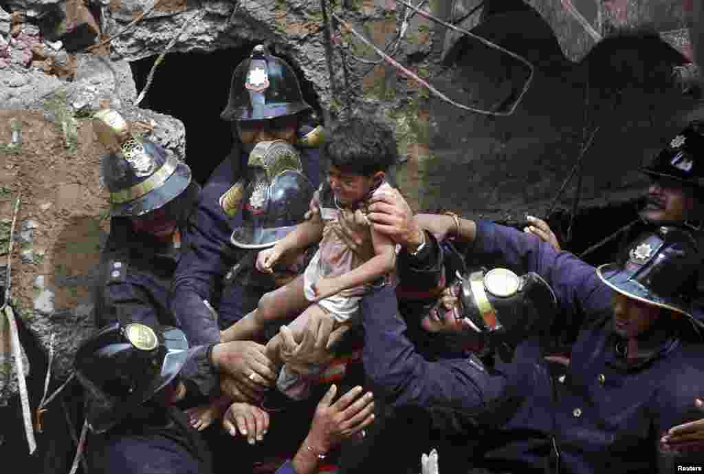 Para petugas penyelamat mengusung seorang anak perempuan yang diselamatkan dari puing-puing di lokasi runtuhnya sebuah bangunan tempat tinggal di Mumbai, India. Apartemen lima lantai itu runtuh di wilayah pusat keuangan, menewaskan setidaknya delapan orang dan membuat puluhan lainnya terperangkap dalam kecelakaan terbaru itu.