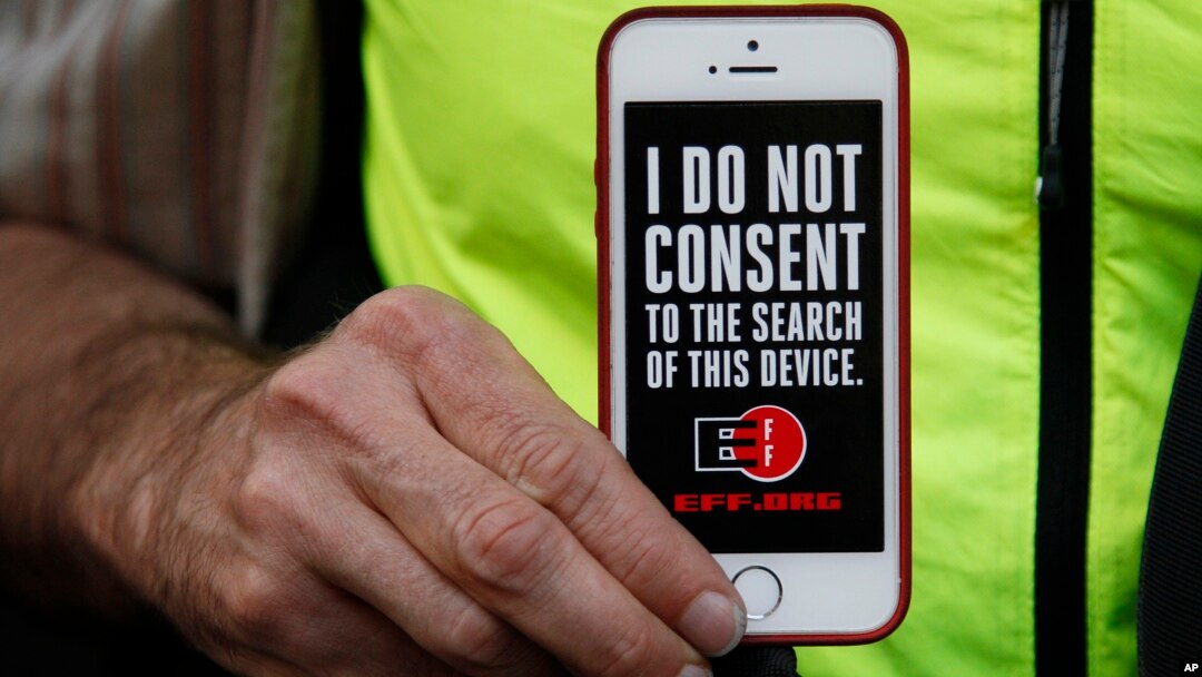 FILE - A man holds up his iPhone during a rally in support of data privacy outside an Apple store in San Francisco, Calif.