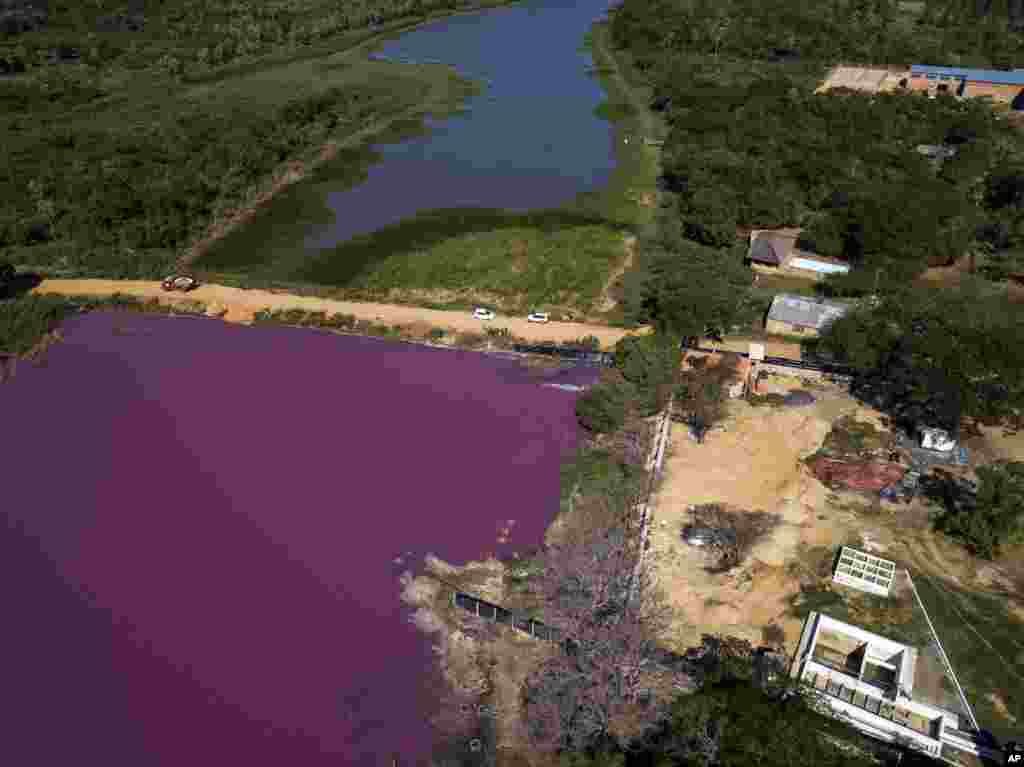 A road divides the Cerro Lagoon and the Waltrading S.A. tannery, bottom right, in Limpio, Paraguay, Aug. 5, 2020. According to Francisco Ferreira, a technician at the National University Multidisciplinary Lab, the color of the water is due to the presence of heavy metals like chromium, commonly used in the tannery process.