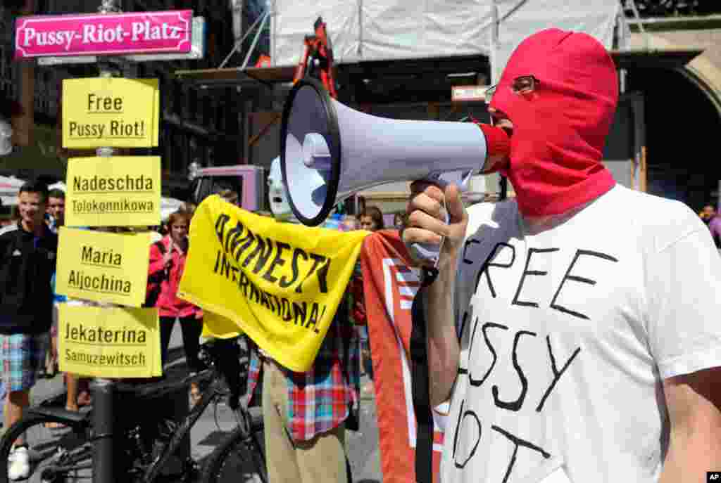 A masked activist from Amnesty International protests next to the street sign of "Pussy-Riot-Platz" in Munich.