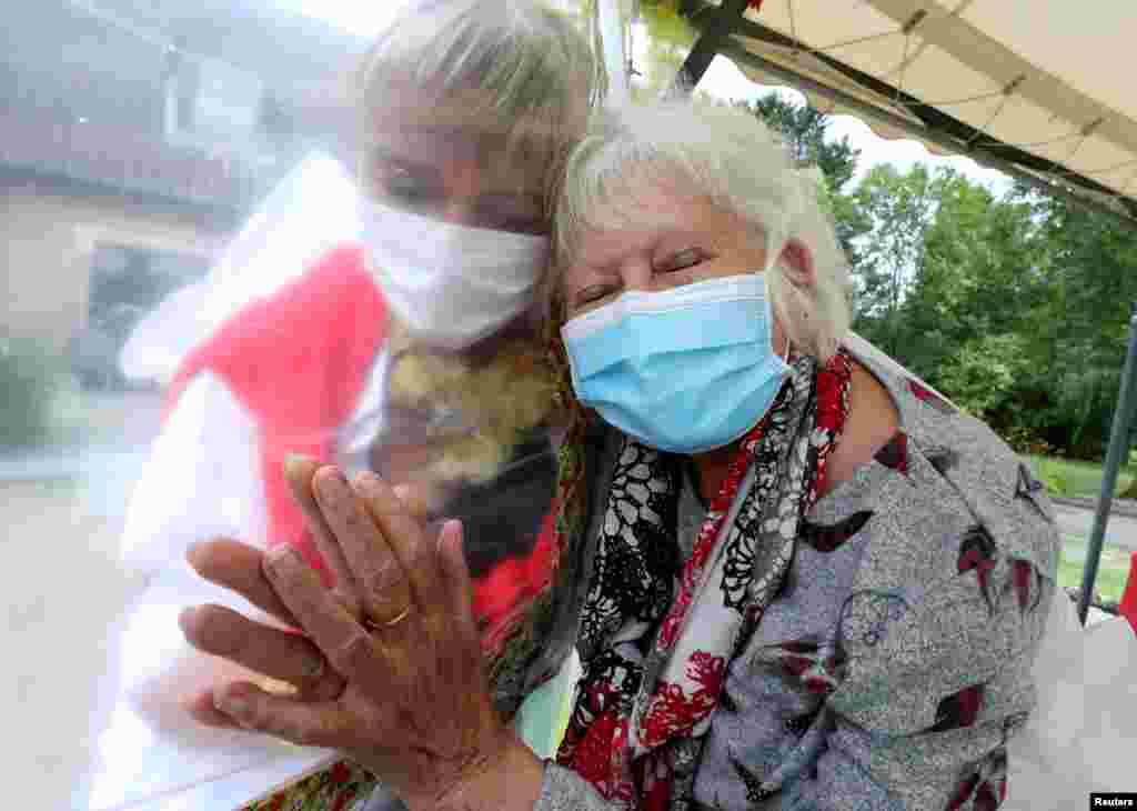 Lily Hendrickx, 83, a resident at Belgian nursing home "Le Jardin de Picardie" hugs Marie-Christine Desoer, the director of the residence, through a wall made with plastic sheets to protect against potential coronavirus disease (COVID-19) infection, in Peruwelz, Belgium, July 1, 2020. 