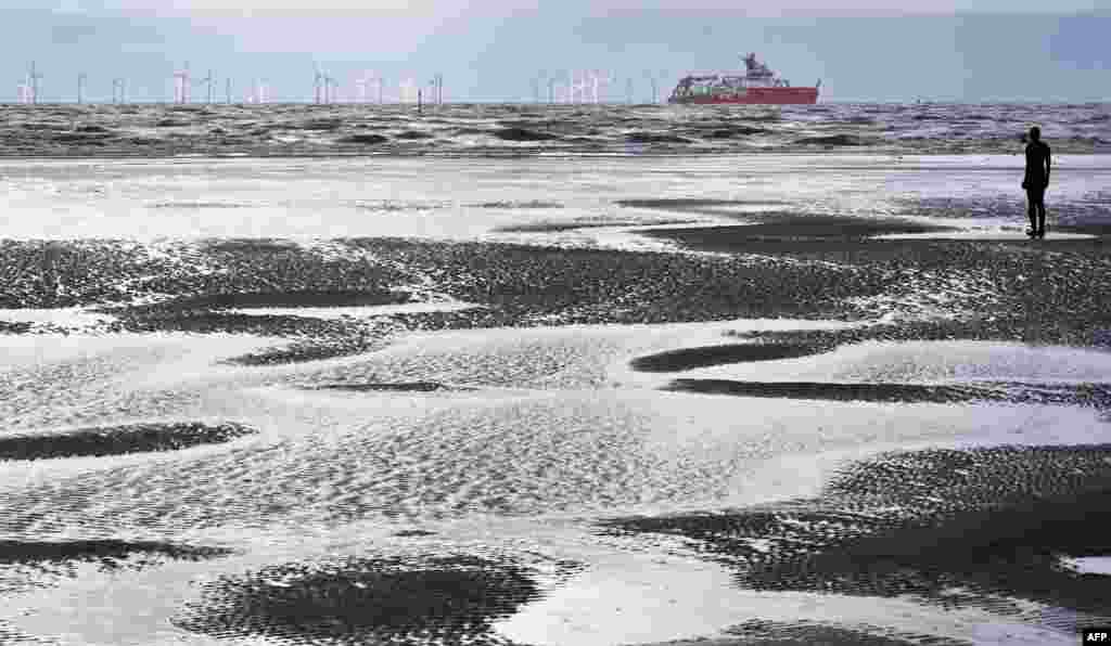 Polar research ship, the RRS Sir David Attenborough, sails out of the River Mersey past Antony Gormley's art installation 'Another Place' at Crosby, north west England.