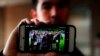 FILE - Amos Cao, son of detained Chinese Rev. John Sanqiang Cao, holds a family photo showing his father (R) in Ann Arbor, Mich., April 10, 2018.