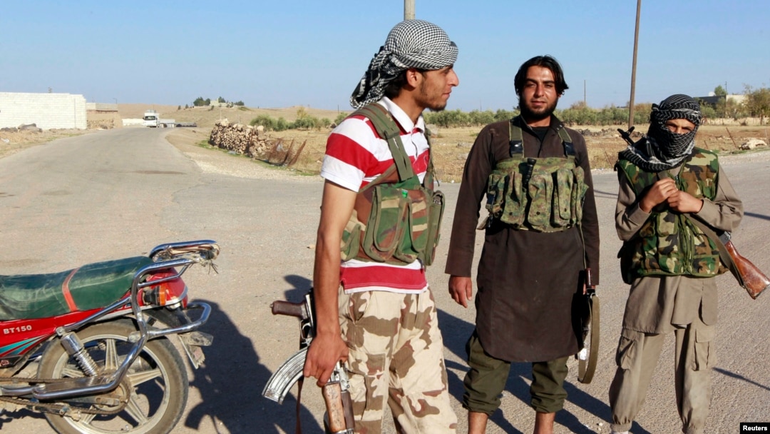 Islamic State fighters stand along a street in the countryside of the Syrian Kurdish town of Kobani, after taking control of the area, Oct. 7, 2014.