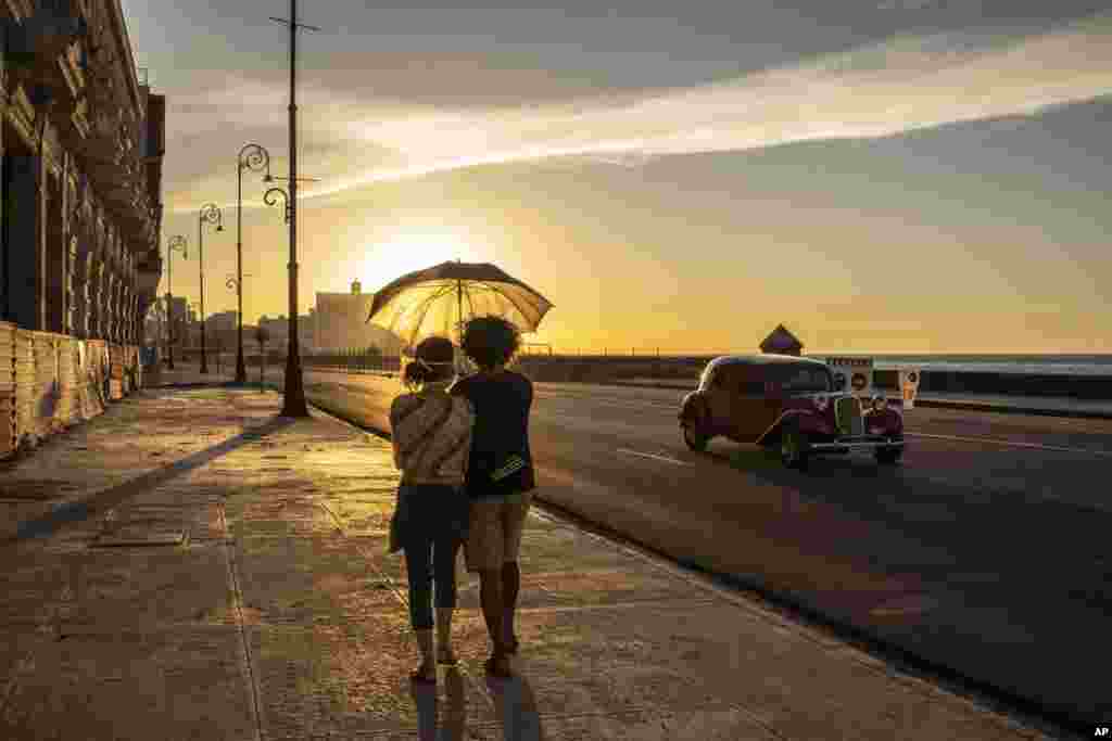 A couple walks on the Malecon seawall at sunset in Havana, Cuba, Aug. 31, 2020.
