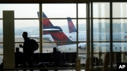 ARCHIVO - Una persona camina por la terminal mientras los planos permanecen en las puertas del Aeropuerto Nacional Ronald Reagan de Washington en Arlington, Virginia, el miércoles 11 de enero de 2023. AP