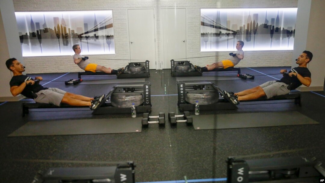 Instructor of CITYROW Atlanta Midtown, Jose Mendoza, center, leads a class as gyms reopen with limited members on Saturday, May 16, 2020, amid the COVID-19 virus in Atlanta. (AP Photo/Brynn Anderson)