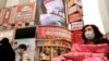 Residents wearing masks past by a screen showing a trailer for the film "Days and Nights in Wuhan" outside a mall in Wuhan in central China's Hubei province on Jan. 22, 2021.