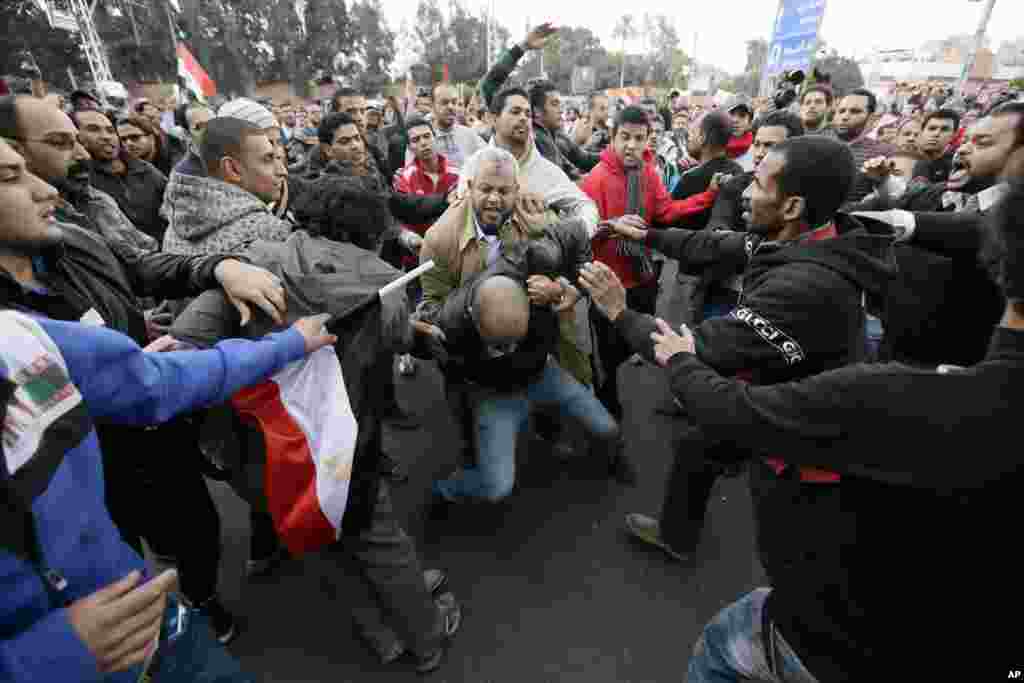 Egyptian President Mohammed Morsi’s supporters beat an opponent, center, during clashes outside the presidential palace, in Cairo, Egypt, Dec. 5, 2012.