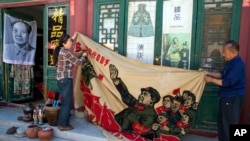 北京商販正在展示一面畫有中國前領導人毛澤東在文革時期的宣傳旗。 （2016年5月16日）
