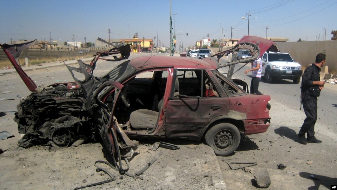 People inspect the site of a car bomb attack on cars lined up at a gas station in the oil rich city of Kirkuk, in northern Iraq, July 10, 2014. 