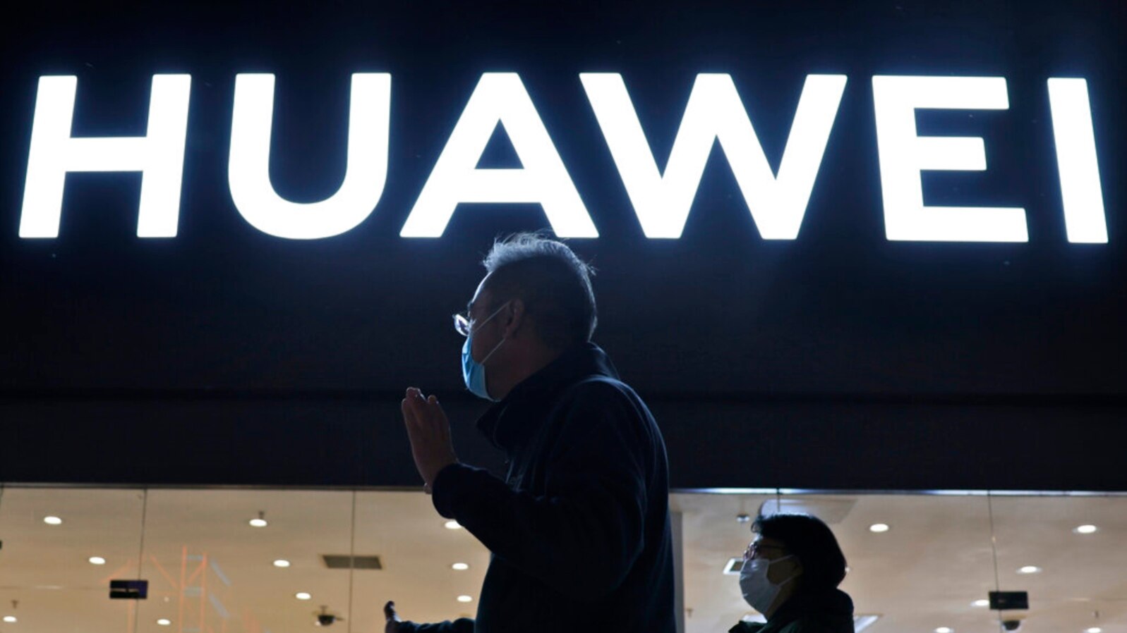 FILE - Residents pass by a Huawei electronics store in Beijing, April 12, 2021. 