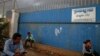 FILE - People wait for garment workers to leave a factory in a suburb of Phnom Penh.