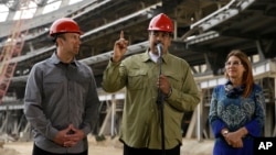 Tareck El Aissami, entonces vicepresidente del gobierno venezolano, escucha al presidente Nicolás Maduro hablar junto a su esposa, Cilia Flores, durante un recorrido por las obras del estadio de béisbol de La Rinconada, en Caracas, el 19 de mayo de 2018.