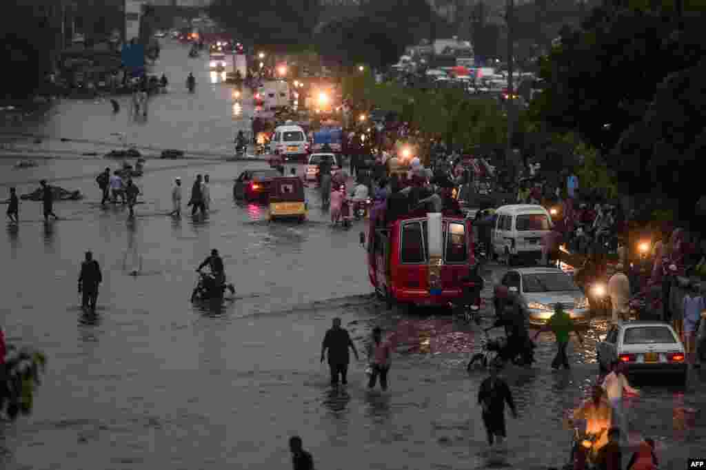 Motorists and pedestrians wade through a flooded street after heavy monsoon rains in the Pakistan's port city of Karachi, Pakistan.