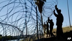 Anggota militer AS memasang beberapa lapis kawat berduri di sepanjang tepi Rio Grande dekat Jembatan Juarez-Lincoln di perbatasan AS-Meksiko, 16 November 2018, di Laredo, Texas. (Foto: AP)