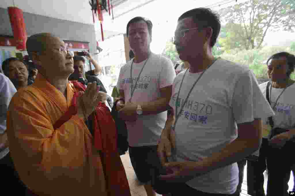 Seorang biksu Buddha menyambut keluarga warga China penumpang pesawat MH370 ketika tiba untuk berdoa di kuil Buddha di Petaling Jaya, Malaysia, 31 Maret 2014.