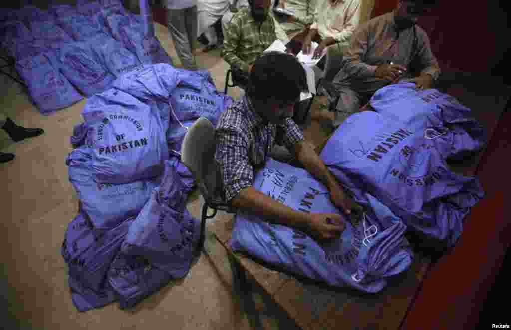 Officials from the Election Commission of Pakistan prepare sacks of stationery materials, before they are transported to polling offices, in the premises of the district city court in Karachi, May 8, 2013.