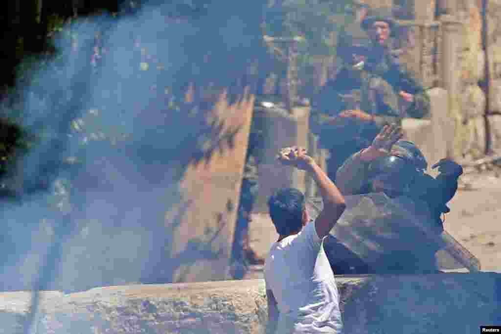 A Palestinian demonstrator hurls stones at Israeli soldiers during a protest in Hebron in the Israeli-occupied West Bank.
