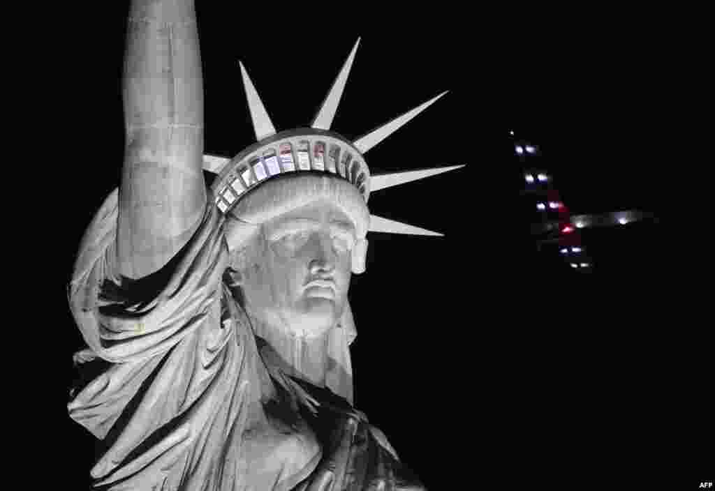 Pesawat tenaga surya 'Impulse 2' terbang di atas patung Liberty sebelum mendarat di bandara JFK di New York.