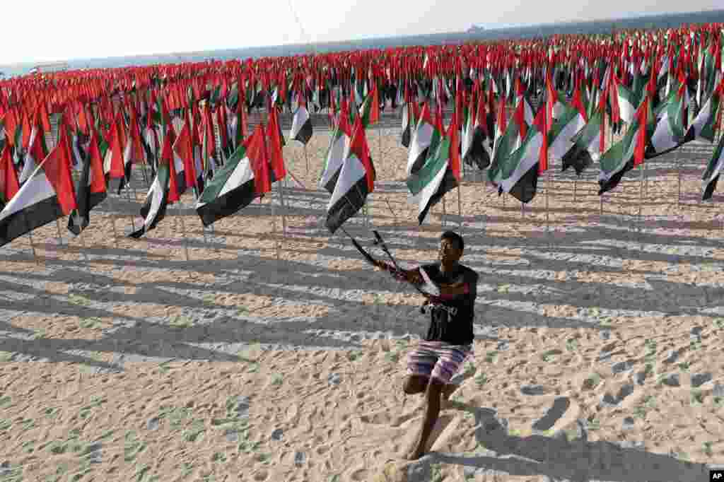 A man manuveurs his kite in Dubai where UAE national flags are set up to celebrate the country's Flag Day.