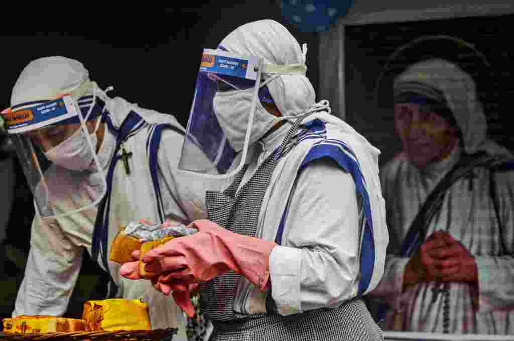 Nuns of the Missionaries of Charity, the order founded by Saint Teresa, wear masks and face shields as precaution against the coronavirus as they distribute food to poor and homeless people in Kolkata, India, on Mother Teresa's 110th birth anniversary.