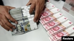 一名中國的銀行職員在點數美元和人民幣。（資料照片） 